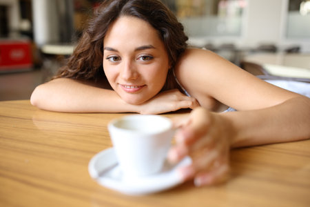 Woman in a coffee shop catching cup on a tableの写真素材