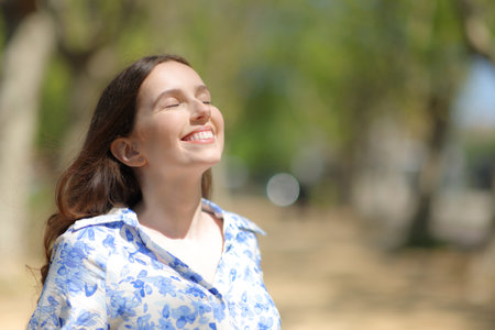 Happy woman breathing fresh air standing alone in a parkの写真素材