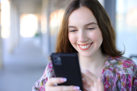 Happy woman using smartphone walking in a streetの写真素材