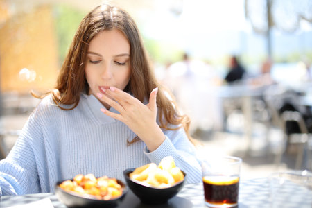 Restaurant customer eating and licking finger in a terraceの写真素材
