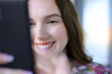 Close up of a happy woman using phone in the streetの写真素材