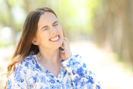 Stressed woman scratching itchy neck in a park on summerの写真素材