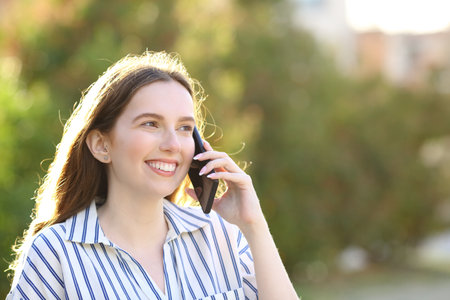 Happy woman talking on cell phone walking in a parkの写真素材
