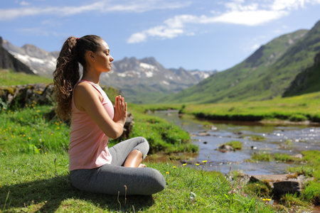 Side view portrait of a yogi beginning yoga exercise on the mountainの写真素材