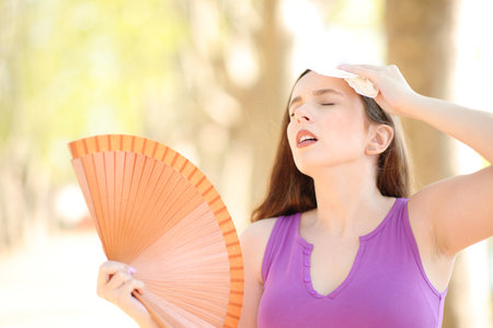 Stressed woman drying sweat with a tissue and fanning a hot summer dayの写真素材