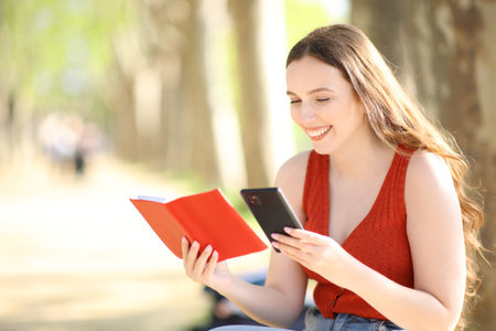 Happy woman checking paper agenda and phone in a parkの写真素材