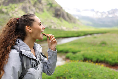 Profile of a hiker eating cereal bar in a valley in the mountainの写真素材