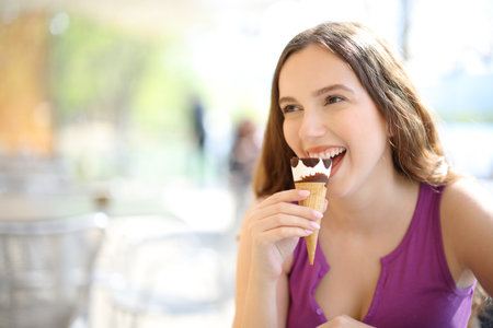 Happy woman eating ice cream in a restaurant terraceの写真素材