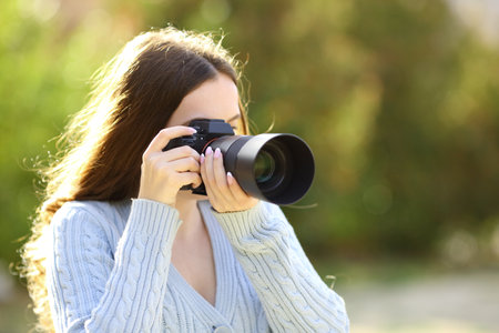 Photographer taking photos with mirrorless camera in a parkの写真素材