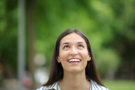 Front view portrait of a happy woman looking abobe in a parkの写真素材