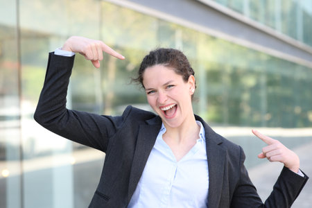 Front view portrait of a proud executive pointing herself in the streetの写真素材