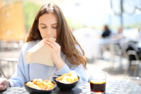 Front view portrait of a restaurant customer cleaning mouth with napkin in terraceの写真素材