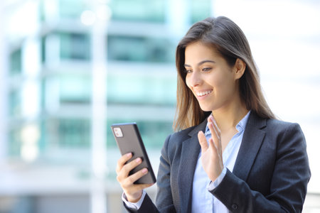 Happy executive waving in a video call on phone in the streetの写真素材