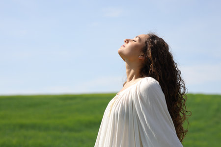 Side view portrait of a single woman breathing fresh air in a green fieldの写真素材