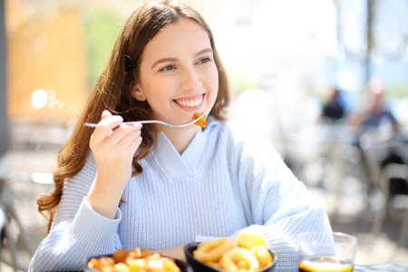 Happy woman eating tapas looking away in a bar terraceの写真素材