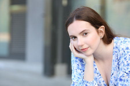 Confident woman looks at camera sitting in the streetの写真素材