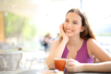 Happy bar customer sitting in a terrace looks awayの写真素材