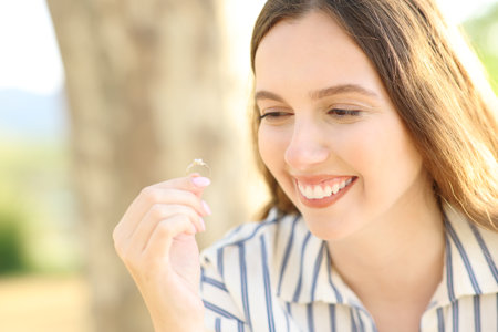 Happy fiancee enjoying looking at engagement ring in natureの写真素材