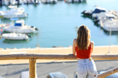 Back view of a woman looking at port on summer vacationの写真素材