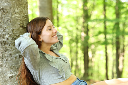 Happy woman resting alone sitting in a green forestの写真素材