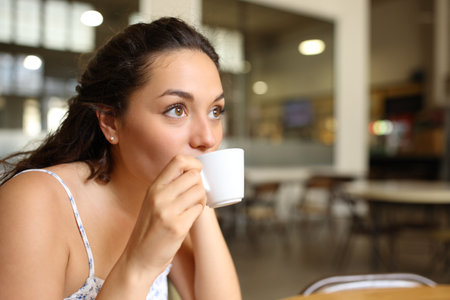 Woman sipping coffee sitting in a bar interiorの写真素材