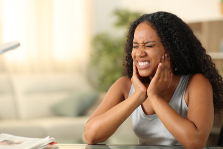 Black woman suffering tmj complaining sitting at homeの写真素材