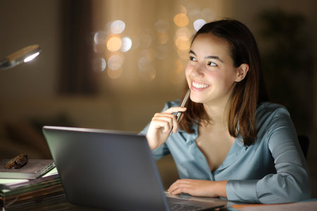 Happy entrepreneur thinking looking at side teleworking in the night at homeの写真素材