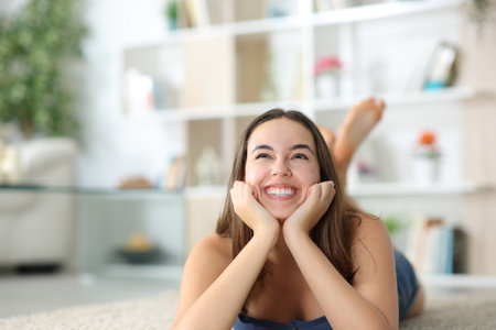 Front view portrait of a happy woman dreaming lying on the floor at homeの写真素材