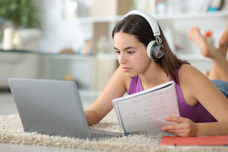 Student e-learning with laptop and headphone comparing notes at homeの写真素材
