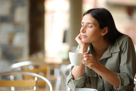 Woman drinking coffee relaxing sitting in a bar terrace with closed eyesの写真素材