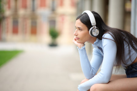 Profile of a relaxed woman with headphone listening podcast in the streetの写真素材