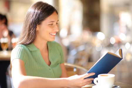Happy woman is reading a book in a bar terraceの写真素材