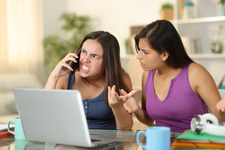 Two angry students claiming talking on phone at homeの写真素材