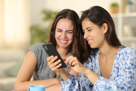 Disgusted women checking nasty cell phone content at homeの写真素材
