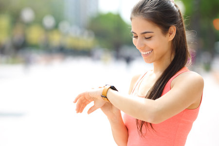 Happy runner checking time on smartwatch on the streetの写真素材