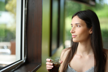 Restaurant customer drinking soda looking away through a windowの写真素材