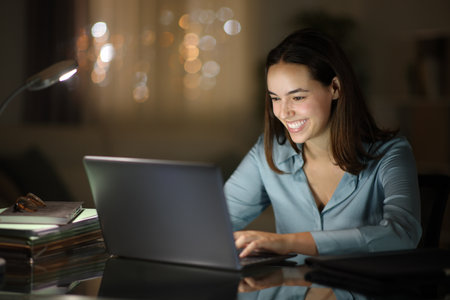 Happy tele worker working in the night with laptop at home officeの写真素材