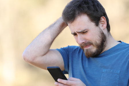 Sad man checking smart phone bad content standing outdoorsの写真素材