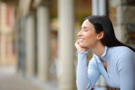 Profile of a happy single woman relaxing sitting in the streetの写真素材