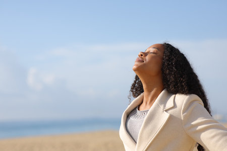 Black woman breathing fresh air in winter on the beach a sunny dayの写真素材