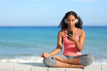Front view portrait of a black yogi preparing yoga video guide on the beach a summer sunny dayの写真素材