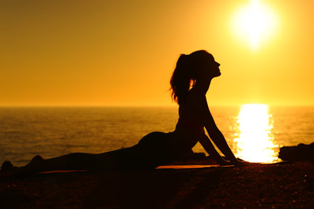 Side view portrait silhouette of a yogi at sunset doing yoga on the beachの写真素材