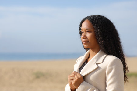 Serious black woman in winter on the beach contemplatingの写真素材