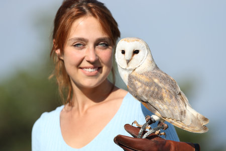 Portrait of a falconer with an owl looking at camera outdoorの写真素材