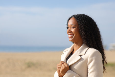 Happy black woman contemplating on the beach in winter a sunny dayの写真素材