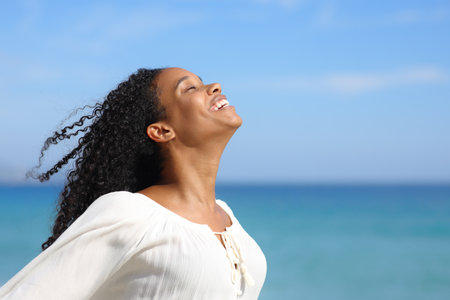 Happy black woman breathing fresh air on the beach a summer sunny dayの写真素材
