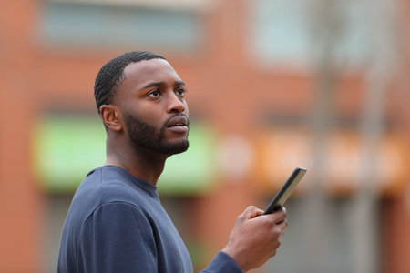 Lost black man searching location on smart phone in the streetの写真素材