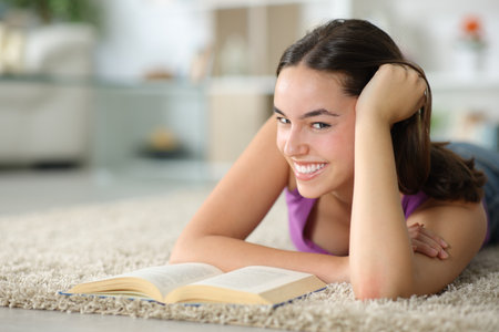 Portrait of a happy woman looking at you lying on the floor at homeの写真素材