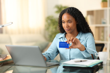 Black tele worker buying with credit card and laptop at homeの写真素材