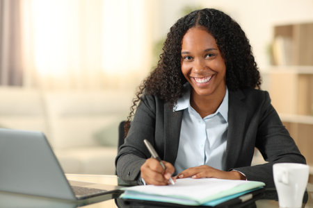 Happy black tele worker signing form looking at you at homeの写真素材